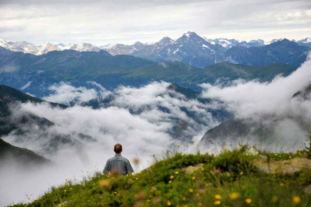 Avusturya Alpleri zirvesinde bulutlara ve karsız dağlara bakan adam, iklim değişikliği 2026.