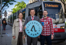 Peter Hanke ve beraberindekiler Avusturya Yuruyor logosuyla tramvay onunde poz veriyor