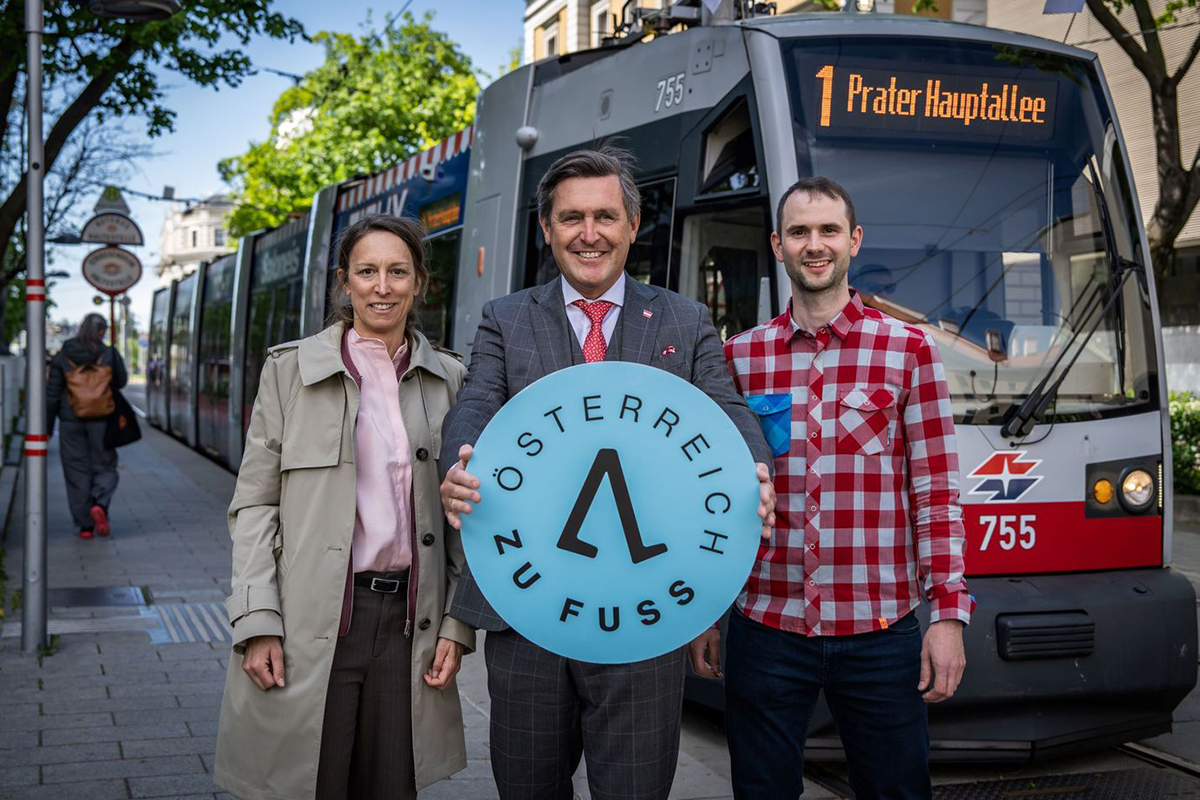 Peter Hanke ve beraberindekiler Avusturya Yuruyor logosuyla tramvay onunde poz veriyor