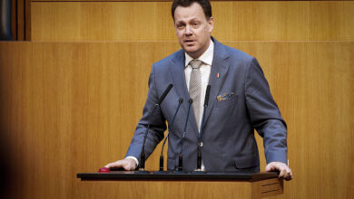 FPÖ Sağlık Sözcüsü Gerhard Kaniak, Avusturya Parlamentosu kürsüsünde takım elbisesiyle mikrofonlar önünde konuşma yapıyor.