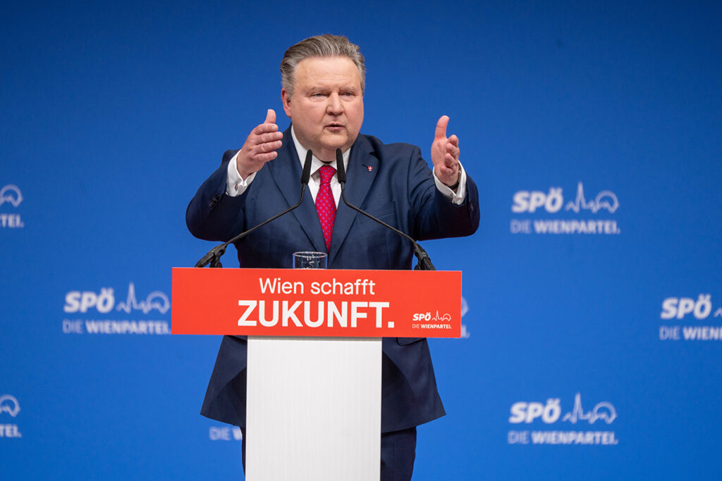 Michael Ludwig, "Wien schafft ZUKUNFT" yazılı kürsüde ellerini açarak hitap ediyor.