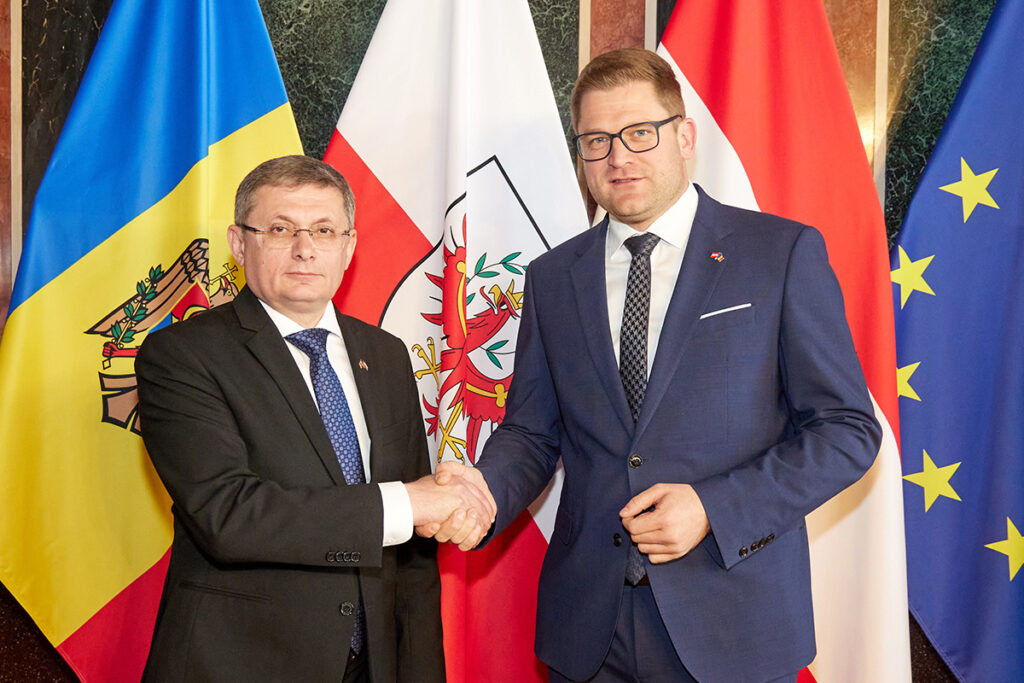 Federal Konsey Başkanı Markus Stotter ve Moldova Parlamento Başkanı Igor Grosu, parlamentoda Moldova ve Avusturya bayraklarının önünde el sıkışırken görülüyor.