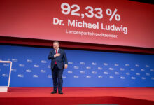 Viyana Belediye Başkanı Dr. Michael Ludwig, arkasında yüzde 92,33 oy oranını gösteren dev ekranın önünde sahnede elini kalbine götürerek teşekkür ediyor.