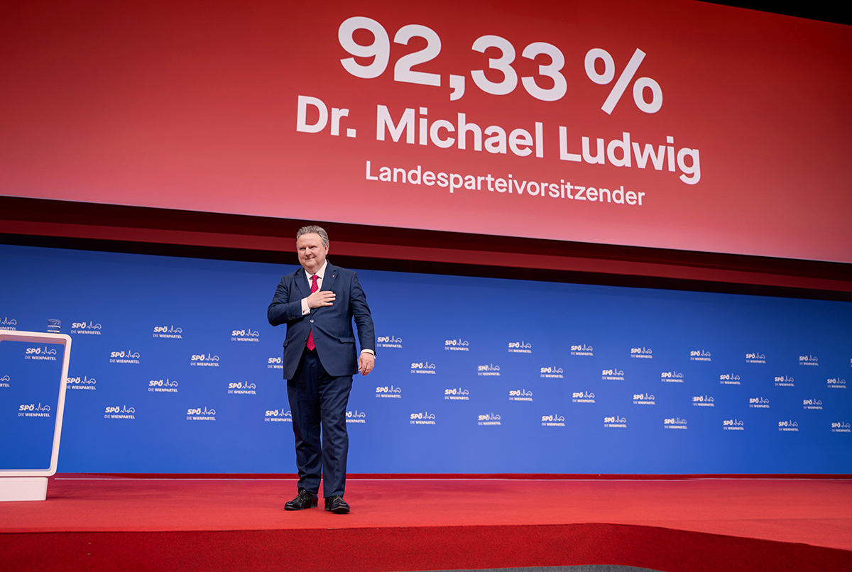 Viyana Belediye Başkanı Dr. Michael Ludwig, arkasında yüzde 92,33 oy oranını gösteren dev ekranın önünde sahnede elini kalbine götürerek teşekkür ediyor.