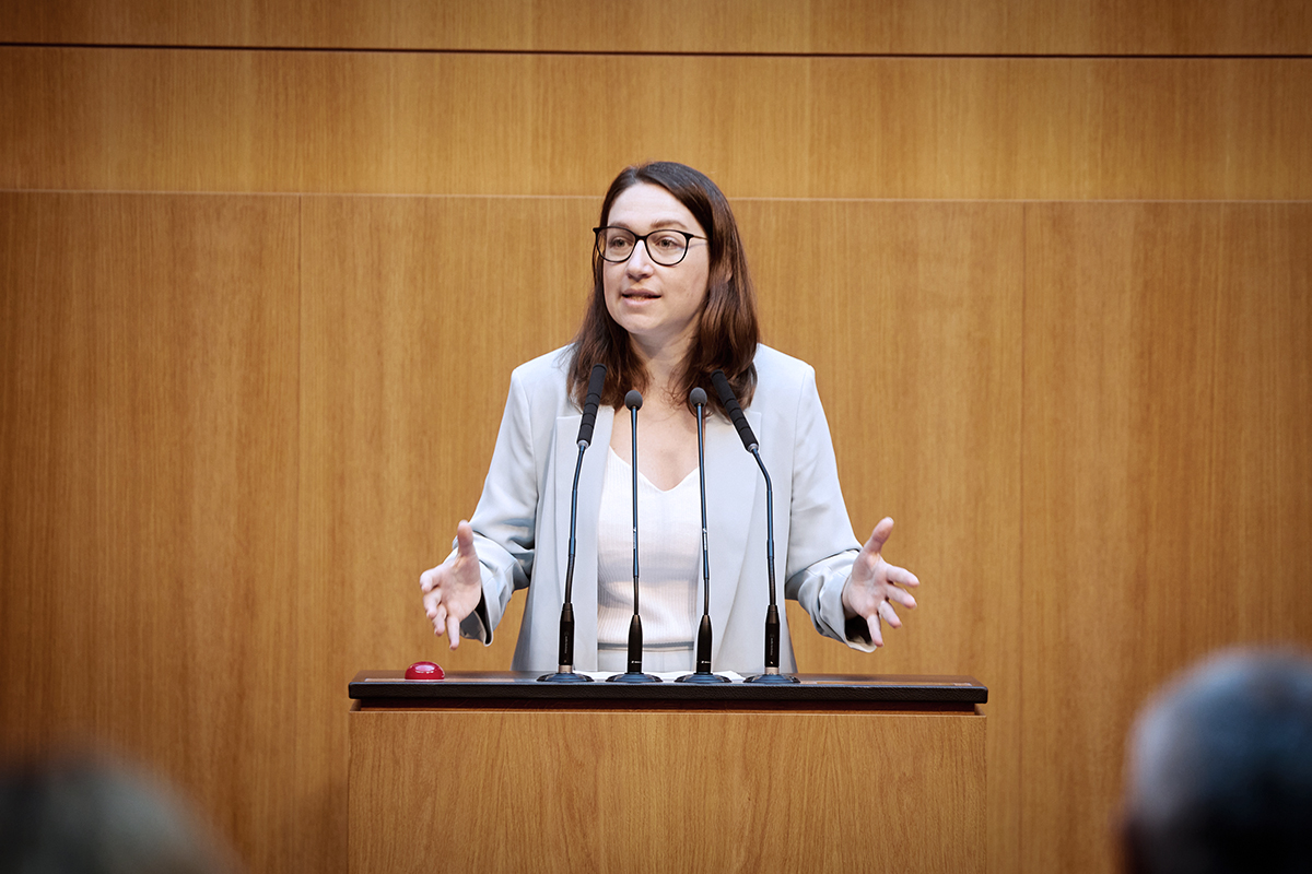 SPÖ Çevre Sözcüsü Julia Herr, kürsüde elleri açık bir jestle nükleer enerji karşıtı konuşma yapıyor. Arka plan ahşap panelli, masada mikrofonlar ve kırmızı bir buton var.
