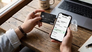 Bir elinde kredi kartı diğer elinde akıllı telefon ile online alışveriş yapan bir kişi ve ekrandaki güvenlik kilidi sembolü.