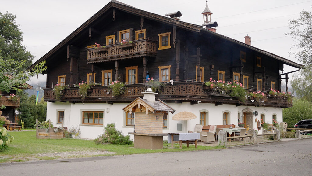 Avusturya'nın Salzburg bölgesinde, balkonları ve pencereleri rengarenk çiçeklerle süslenmiş iki katlı, geleneksel ahşap ve taş mimarili Alp çiftlik evi.