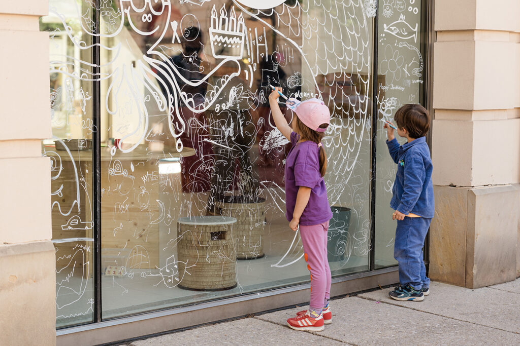 Viyana MuseumsQuartier çocuk müzesi sanat atölyesinde cam duvar boyayan çocuklar.
