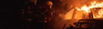 Avusturya'da gece karanlığında alevler içindeki yanan otomobili hortumla söndürmeye çalışan iki itfaiyeci temsili kaza fotoğrafı