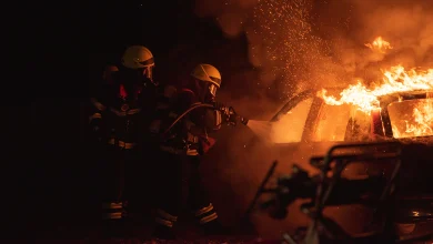 Avusturya'da gece karanlığında alevler içindeki yanan otomobili hortumla söndürmeye çalışan iki itfaiyeci temsili kaza fotoğrafı