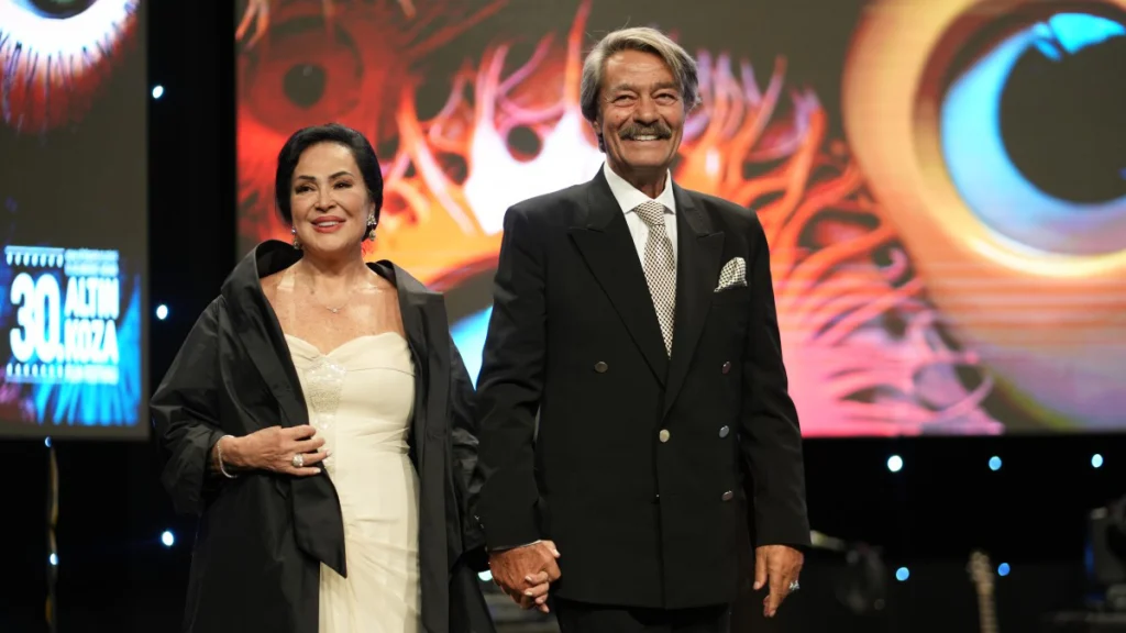 Kadir İnanır ve Türkan Şoray Adana Altın Koza Film Festivali sahnesinde el ele yürürken.