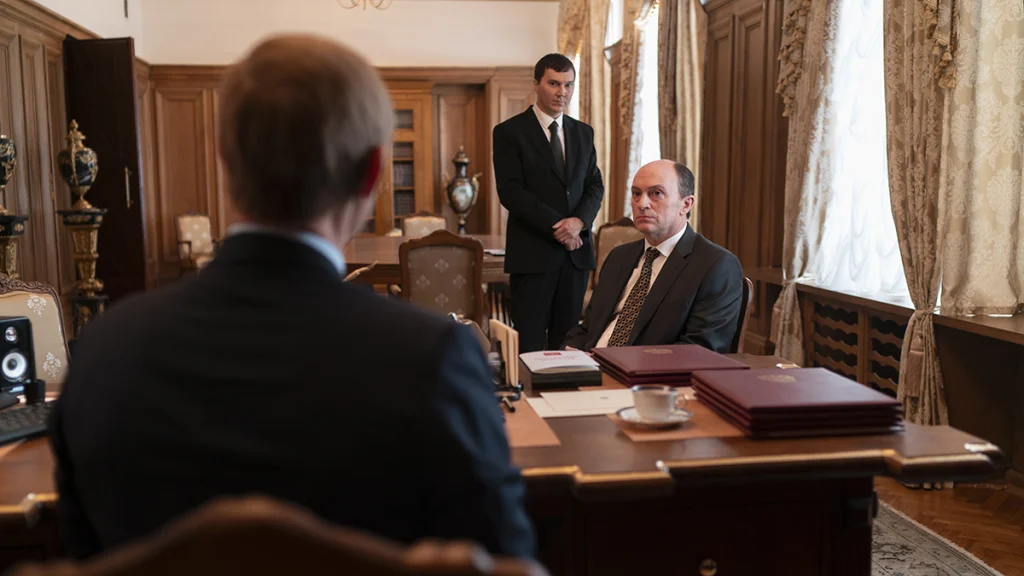 Kremlin'in Büyücüsü filminde makam odasında oturan oligarklar ve ayakta bekleyen Vadim Baranov
