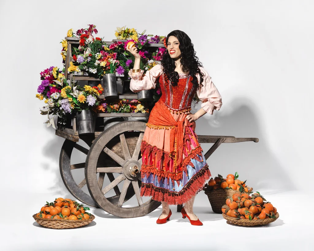 3. Viyana Opera Yazı festivalinde sahnelenecek Carmen operasının başrol karakterini geleneksel İspanyol kostümü, çiçekli bir araba ve portakal sepetleriyle gösteren tanıtım fotoğrafı.