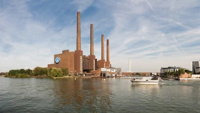 Volkswagen Wolfsburg fabrikası dev bacaları ve bina üzerindeki VW logosu, şirketin geleceği risk altında haber görseli.