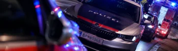 Avusturya'da gece vaktinde mavi ışıkları yanan bir polis arabası ve arka planda duran ambulans ile trafik kazası müdahale sahnesi.