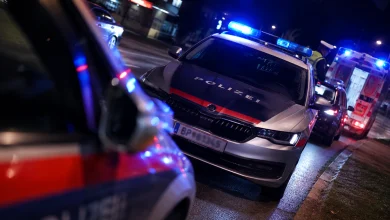 Avusturya'da gece vaktinde mavi ışıkları yanan bir polis arabası ve arka planda duran ambulans ile trafik kazası müdahale sahnesi.