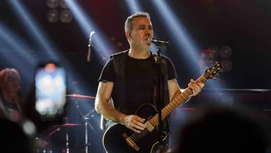 Haluk Levent konser sırasında sahnede elinde gitar mikrofonla şarkı söylerken.