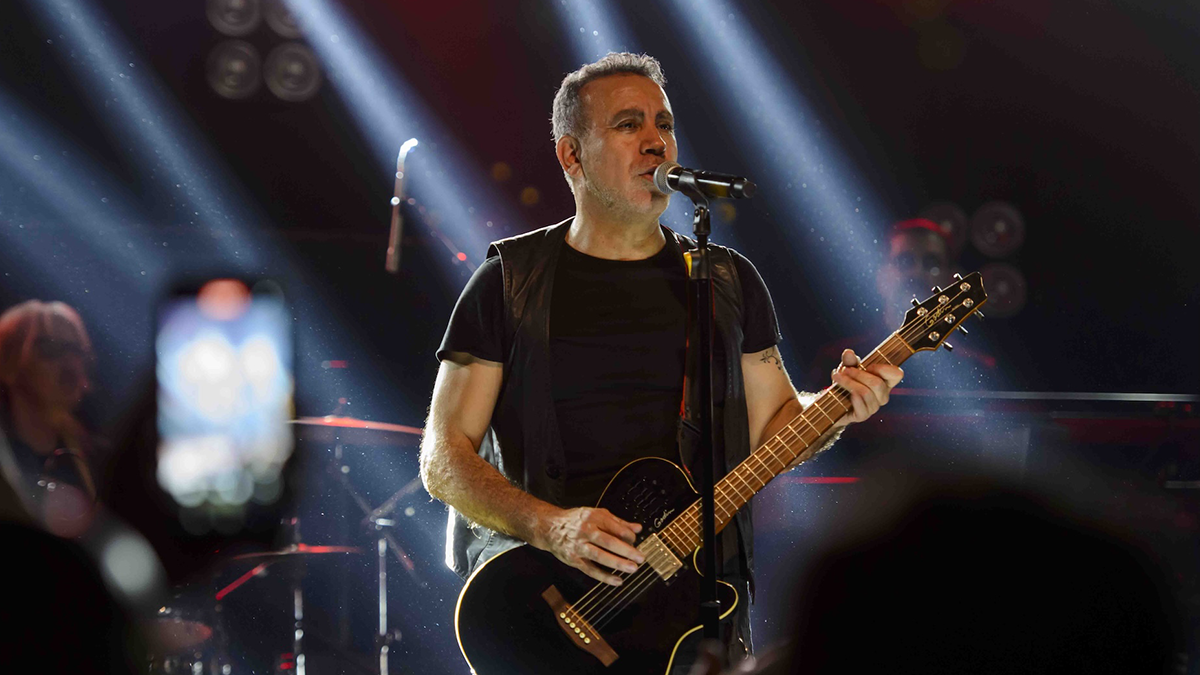 Haluk Levent konser sırasında sahnede elinde gitar mikrofonla şarkı söylerken.