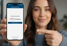 Akıllı telefonunda ID Austria dijital kimlik uygulamasını gösteren ve işaret eden gülümseyen bir kadın.